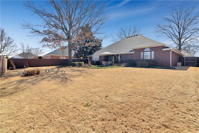 rear view of house with brick siding and a fenced backyard