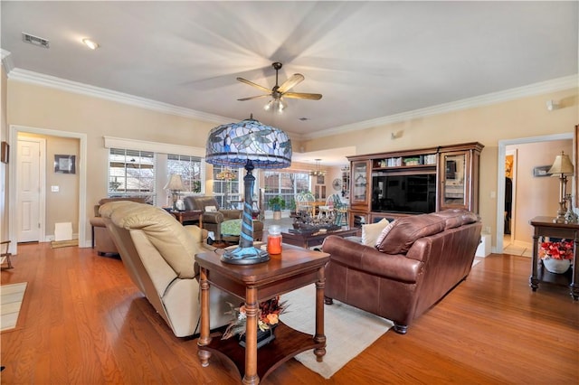 living area with visible vents, ornamental molding, a ceiling fan, and light wood finished floors