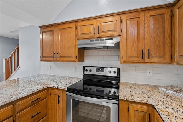 kitchen featuring under cabinet range hood, stainless steel electric range oven, brown cabinetry, and vaulted ceiling