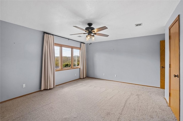 spare room featuring baseboards, light colored carpet, visible vents, and ceiling fan