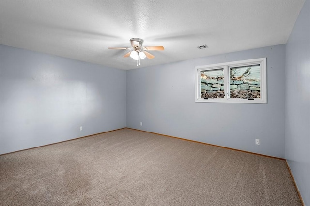 carpeted spare room featuring a ceiling fan, visible vents, and a textured ceiling