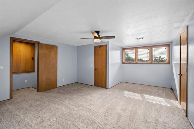 interior space featuring a closet, visible vents, a textured ceiling, and carpet