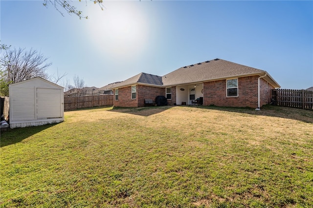 rear view of property featuring an outbuilding, a fenced backyard, a storage shed, a lawn, and brick siding