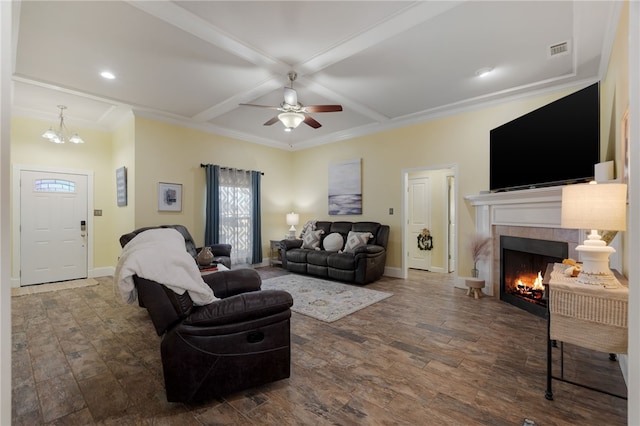 living area featuring wood finished floors, visible vents, coffered ceiling, a fireplace, and ceiling fan with notable chandelier