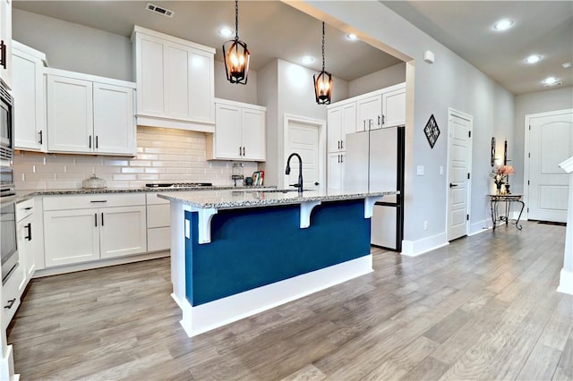 kitchen featuring visible vents, light stone countertops, light wood-type flooring, appliances with stainless steel finishes, and a sink