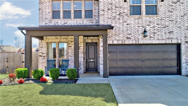 entrance to property with concrete driveway, a garage, a lawn, and brick siding