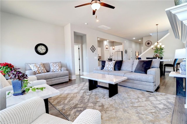 living area with visible vents, light wood-style flooring, ceiling fan with notable chandelier, recessed lighting, and baseboards