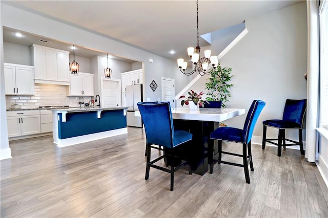 dining area with recessed lighting, light wood-type flooring, baseboards, and a chandelier