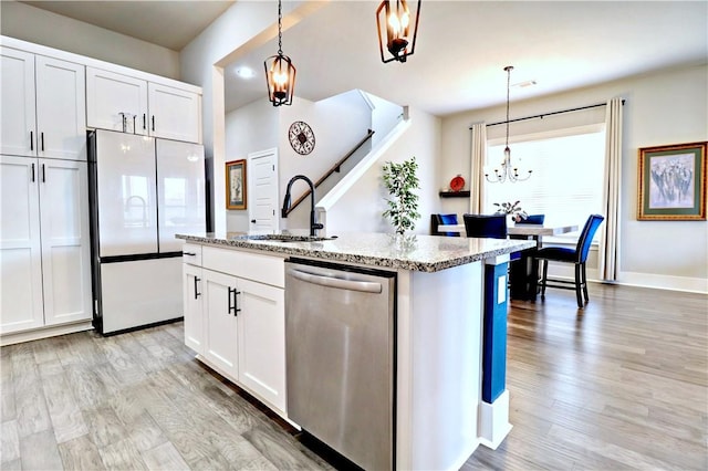 kitchen featuring light stone countertops, dishwasher, light wood-style flooring, freestanding refrigerator, and a sink