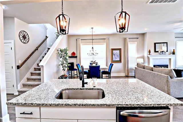 1431 Cave Stream Dr, Cave Springs, AR 72718 - kitchen with stainless steel dishwasher, open floor plan, a sink, wood finished floors, and baseboards