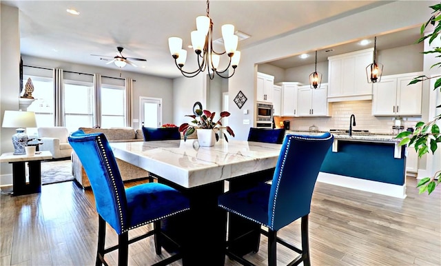 dining space with recessed lighting, a ceiling fan, light wood-type flooring, and a chandelier