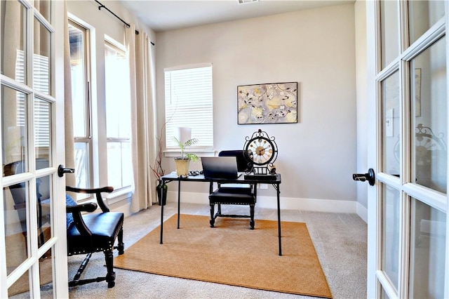 home office with plenty of natural light, light colored carpet, french doors, and baseboards