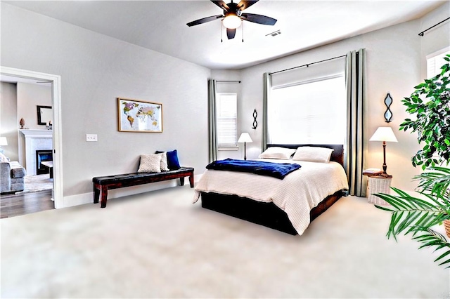 carpeted bedroom featuring visible vents, baseboards, a ceiling fan, and a glass covered fireplace