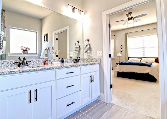 bathroom featuring ensuite bath, ceiling fan, tile patterned floors, double vanity, and baseboards