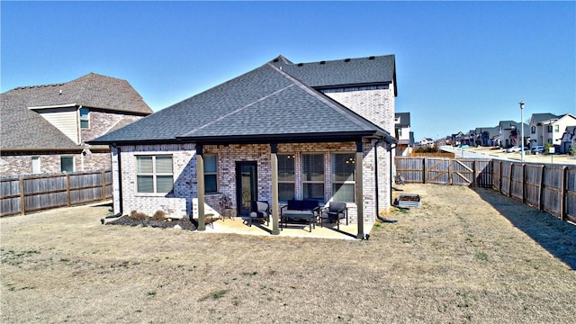 back of house with a shingled roof, a fenced backyard, a lawn, and a patio area