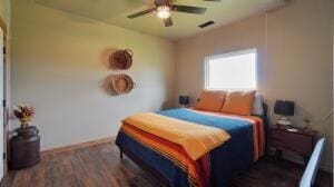 bedroom with visible vents, baseboards, dark wood-type flooring, and a ceiling fan