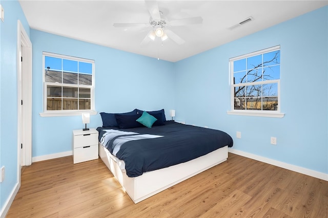 bedroom with visible vents, baseboards, wood finished floors, and a ceiling fan