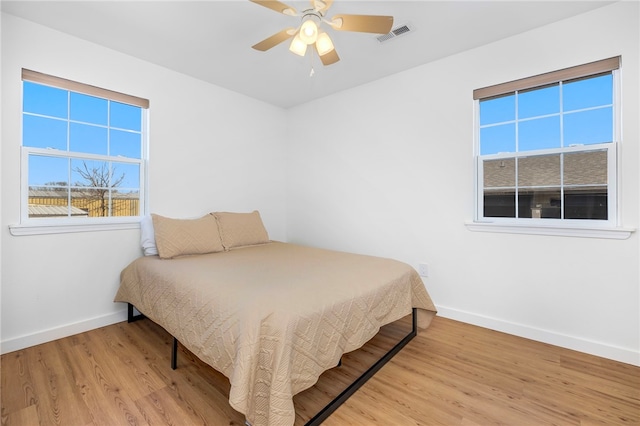 bedroom with visible vents, a ceiling fan, baseboards, and wood finished floors