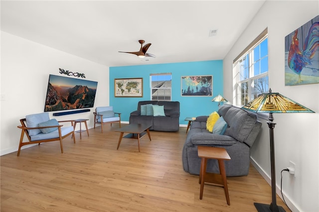 living room with visible vents, baseboards, light wood-style floors, and a ceiling fan