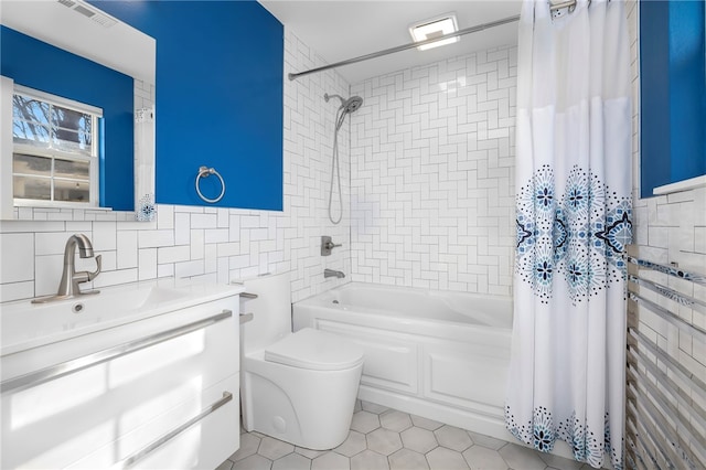 bathroom with visible vents, vanity, tile walls, and shower / bath combo with shower curtain