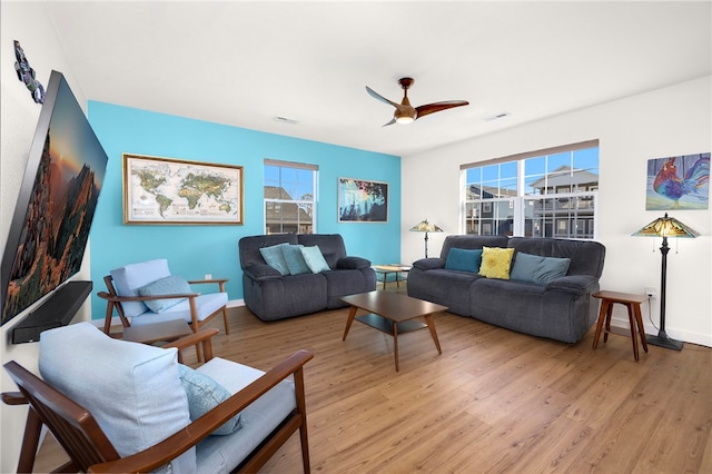 living room featuring baseboards, visible vents, a ceiling fan, and light wood-style floors