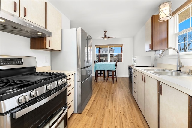 kitchen featuring stainless steel gas range oven, under cabinet range hood, light countertops, and a sink