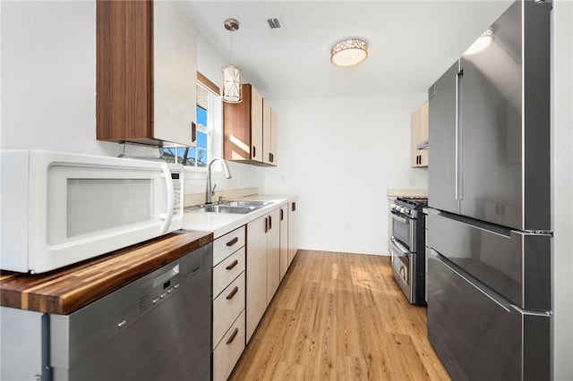 kitchen featuring visible vents, a sink, light wood-style floors, appliances with stainless steel finishes, and butcher block counters