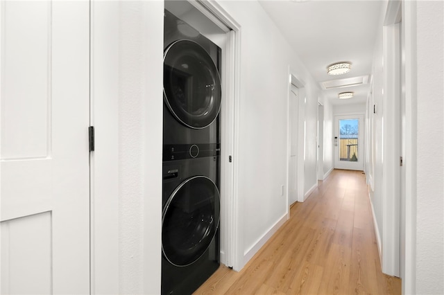 laundry area with stacked washer and clothes dryer, light wood-style flooring, baseboards, attic access, and laundry area