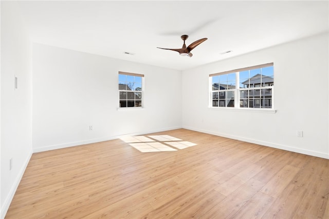 spare room featuring visible vents, a ceiling fan, baseboards, and wood finished floors