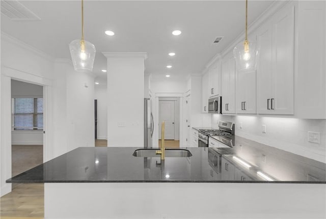 kitchen featuring visible vents, ornamental molding, decorative backsplash, stainless steel appliances, and a sink