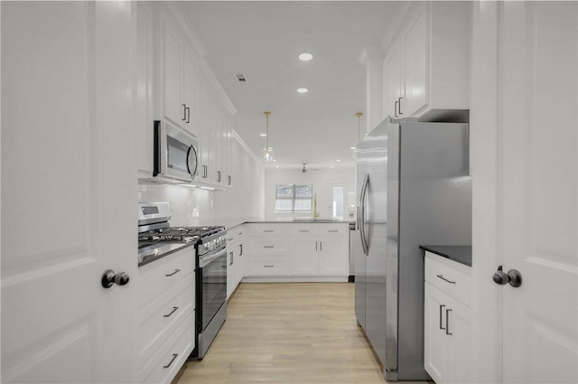 kitchen with backsplash, light wood-style flooring, a peninsula, stainless steel appliances, and white cabinetry