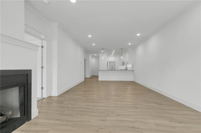 unfurnished living room featuring recessed lighting, ornamental molding, a fireplace, and light wood finished floors