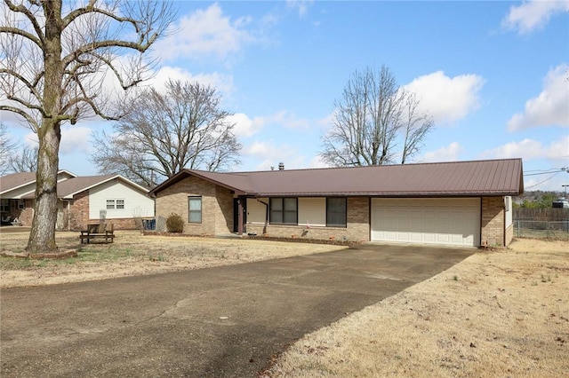 single story home featuring brick siding, driveway, metal roof, and a garage