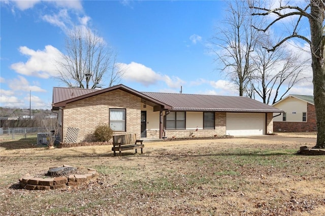 single story home featuring metal roof, brick siding, an attached garage, and fence