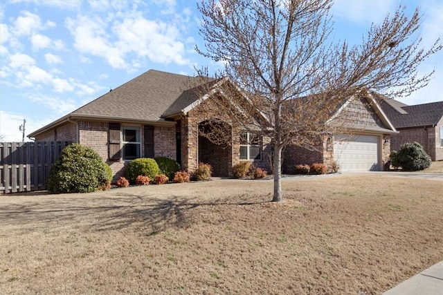 ranch-style house featuring brick siding, a front lawn, fence, a garage, and driveway