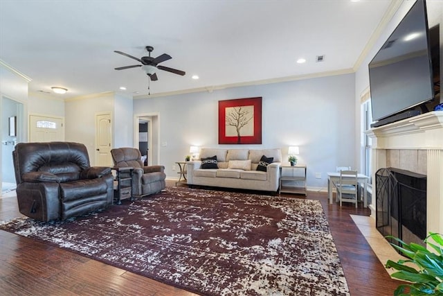 living area featuring visible vents, ornamental molding, a tile fireplace, and wood finished floors