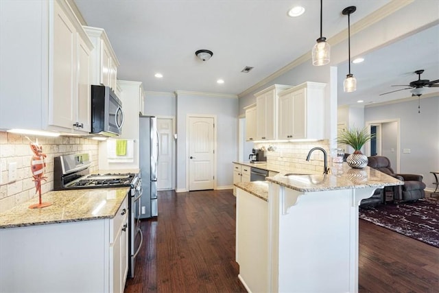 kitchen with a breakfast bar area, a peninsula, a sink, stainless steel appliances, and white cabinetry