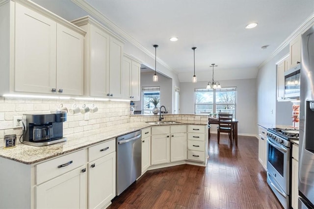 kitchen featuring ornamental molding, a sink, backsplash, stainless steel appliances, and a peninsula