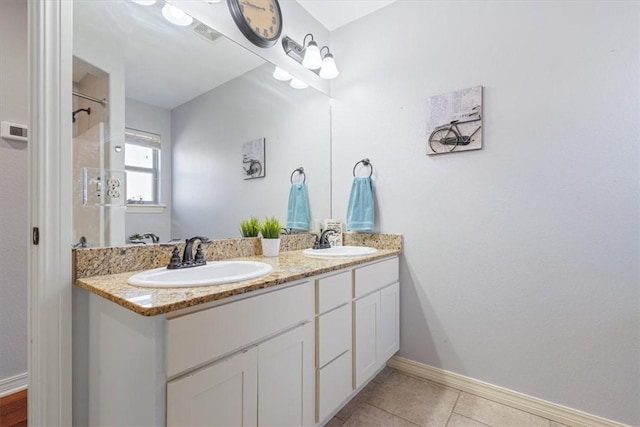 bathroom with tile patterned flooring, double vanity, baseboards, and a sink