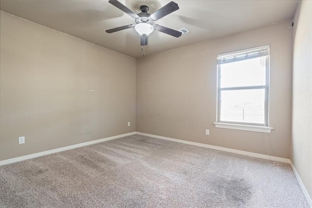 carpeted empty room featuring visible vents, a ceiling fan, and baseboards