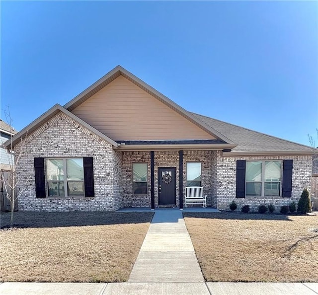 ranch-style house featuring brick siding and a shingled roof