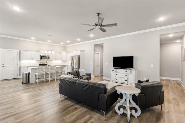 living area with crown molding, baseboards, ceiling fan, recessed lighting, and light wood-style floors
