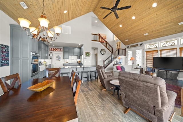 dining room featuring visible vents, stairway, ceiling fan with notable chandelier, wooden ceiling, and wood finished floors