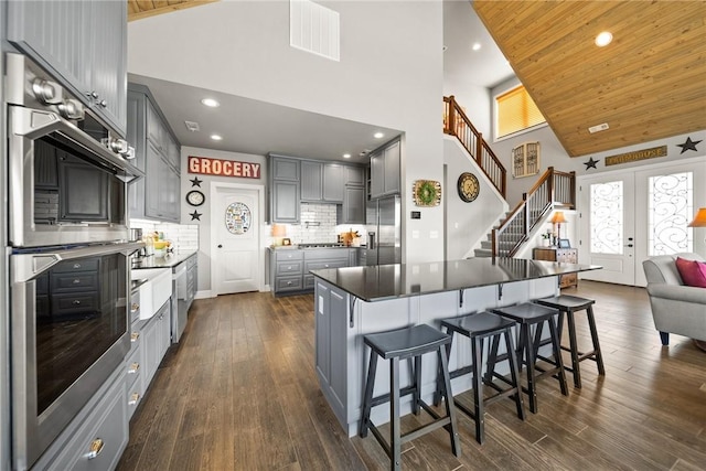 kitchen featuring visible vents, high vaulted ceiling, gray cabinetry, dark wood finished floors, and appliances with stainless steel finishes