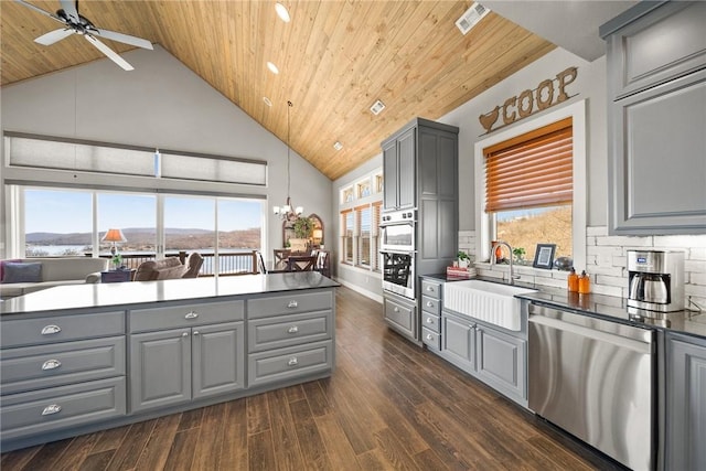 kitchen with dark countertops, gray cabinets, stainless steel appliances, and a sink