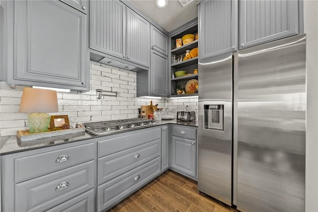 kitchen with gray cabinets, open shelves, dark wood finished floors, stainless steel appliances, and decorative backsplash