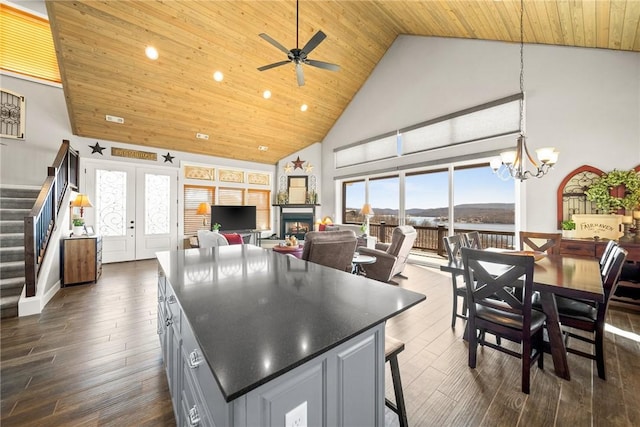 kitchen with high vaulted ceiling, dark wood-type flooring, wood ceiling, ceiling fan with notable chandelier, and a center island