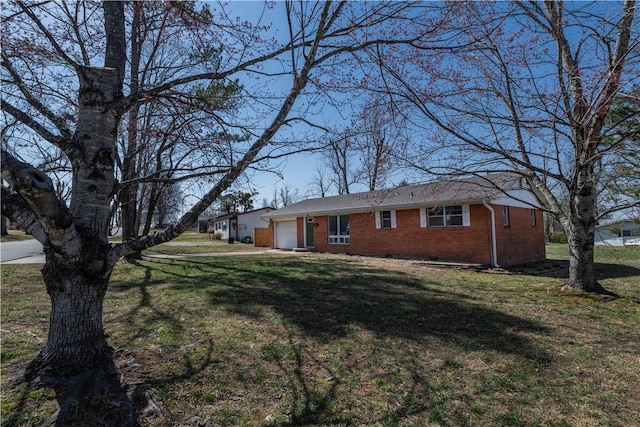 view of front of property featuring a front lawn, an attached garage, and brick siding