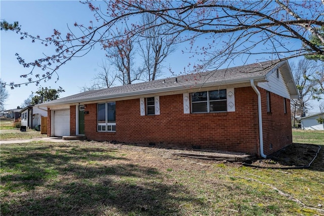 ranch-style house featuring a front yard, an attached garage, brick siding, and crawl space