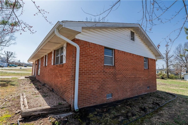 view of side of home featuring brick siding and crawl space